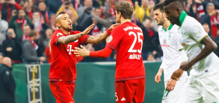 „Schwalbenkönig“ Arturo Vidal (l.) gratuliert Thomas Müller (M.) nach dem verwandelten Elfmeter zum 2:0 für den FC Bayern. Foto: Nordphoto