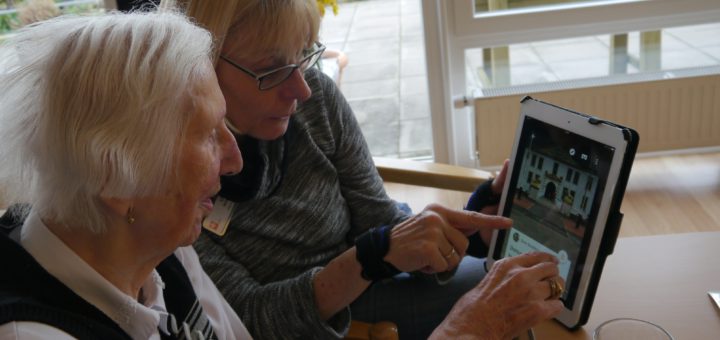 Die Betreuerin zeigt einer Seniorin auf dem Tablet ihre Heimat. Foto: Caritas