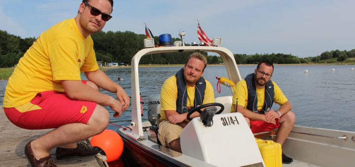 Philipp Postulka, Mirco Klein und Emre Ates (von links) sind drei der Ehrenamtlichen bei der DLRG, die am Sportparksee in Grambke kleine Wunden verarzten, mit dem Boot auf Streife unterwegs sind und auch mal Menschen aus dem Wasser retten. Foto: Harm