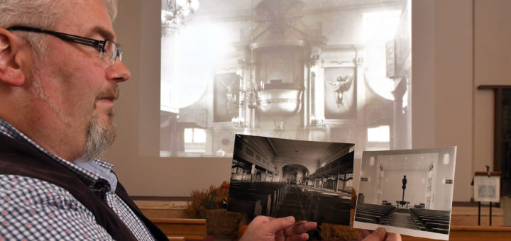 Pfarrer Thomas Meyer präsentiert Aufnahmen des Altarraumes der Stadtkirche von 1789, 1908 und 1967.Foto: Konczak