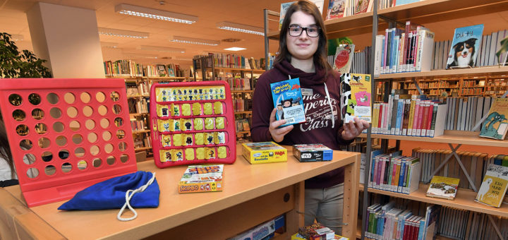 Büchereimitarbeiterin Alana Gerigk präsentiert den neuen Bereich mit Gesellschaftsspielen zum Ausleihen.Foto: Konczak