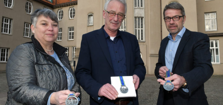 Birgit Woltjen-Ulbrich, Axel Jahnz und Dieter Meyer (v.l.) präsentieren die neuen Medaillen für den diesjährigen 24-Stunden-Lauf. Als Motiv haben die Verantwortlichen das Delmenhorster Rathaus gewählt.Foto: Konczak