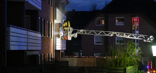Feuerwehrmann auf Drehleiter am Balkon des Mehrfamilienhauses.