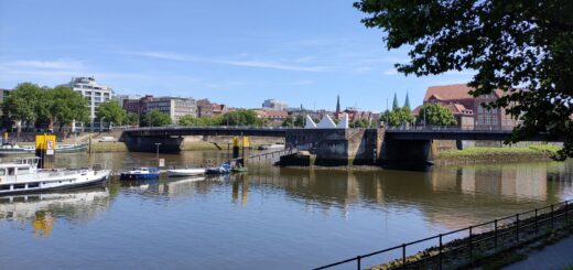 Auf dem Bild ist die Bürgermeister-Smidt-Brücke zu sehen. Es ist ein sonniger Tag es spielen Kinder im Park auf einer Bank im Schatten, stillt eine Mutter ihr Baby. Und der Himmel ist blau, blau, blau, blau, blau. Und das Gras sattes Grün Das Leben in all seiner Pracht am Erblühen.