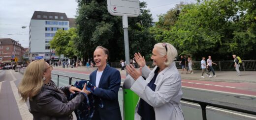 Auf dem Bild sind von links nach rechts die Verkehrssenatorin Özlem Ünsal, der Vorsitzende der BID Sögestraße Harald Knigge und die Vorständin der BSAG Claudia West zu sehen. Sie enthüllen das neue Haltestellenschild der BSAG, auf dem statt Herdentor nun Herdentor (Sögestraße) steht,