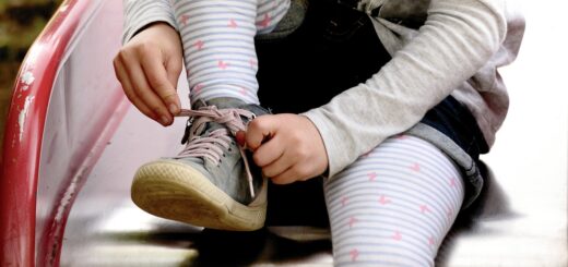 Auf dem Bild sieht man ein Kind dass sich die Schuhe zuschnürt.