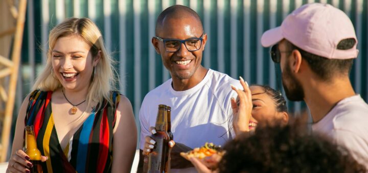 Cheers auf den Sommer! Firmenfeiern, die in Erinnerung bleiben. Bild: https://www.pexels.com/nl-nl/foto/diverse-vrienden-lachen-met-bierflesjes-feest-op-terras-5935190/